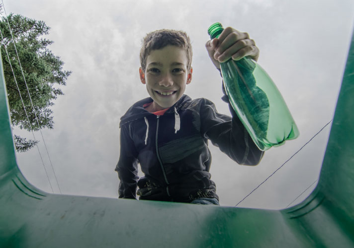 Niño colocando una botella de PET en un bote de reciclaje